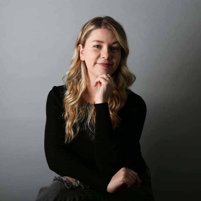Portrait of a smiling woman with long wavy blonde hair in a black sweater