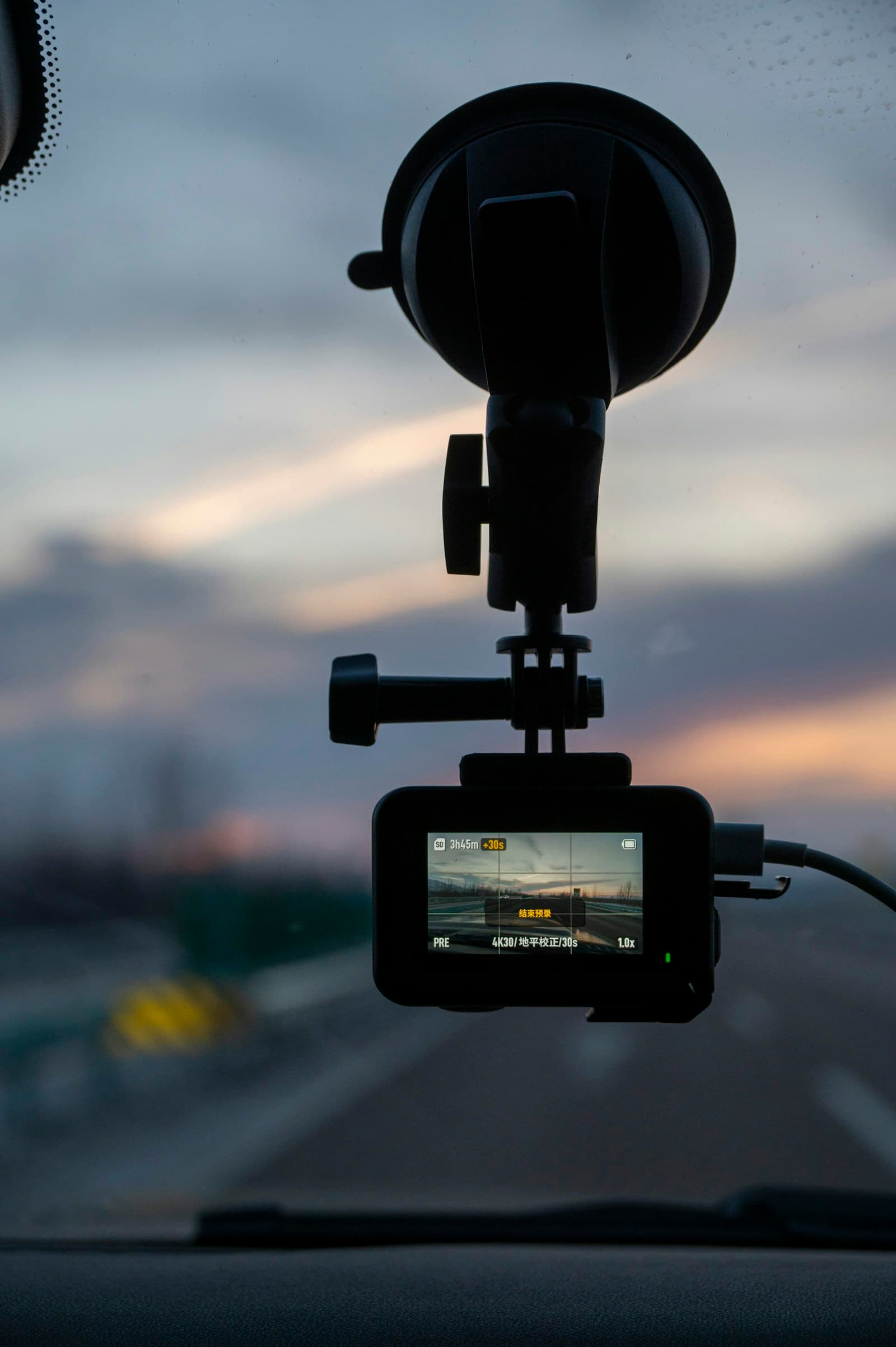 Action camera mounted on a car windshield at sunset