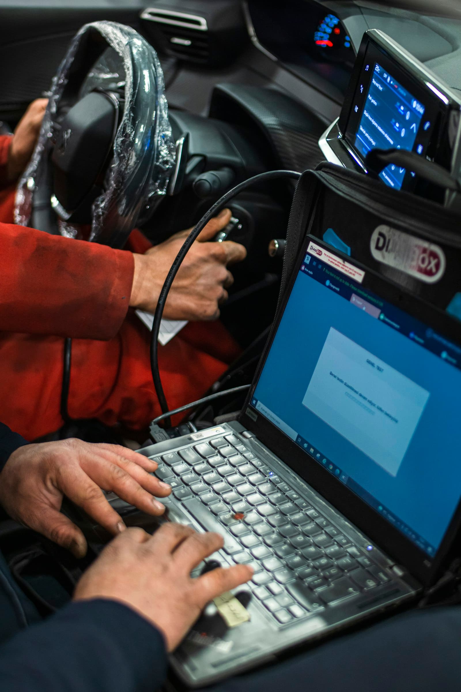 Technician connecting a laptop to a vehicle's diagnostics port