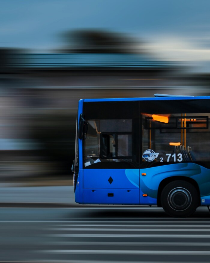 City bus driving down a street next to a tall building
